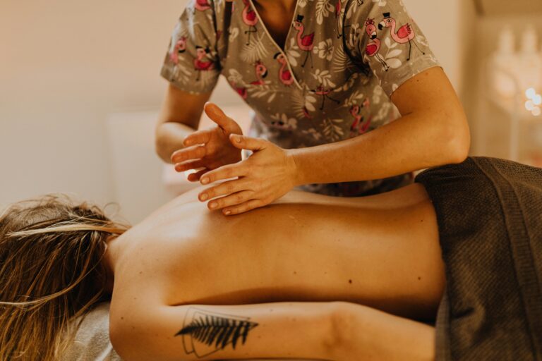 A relaxing massage therapy session with a therapist treating a tattooed woman in a spa.